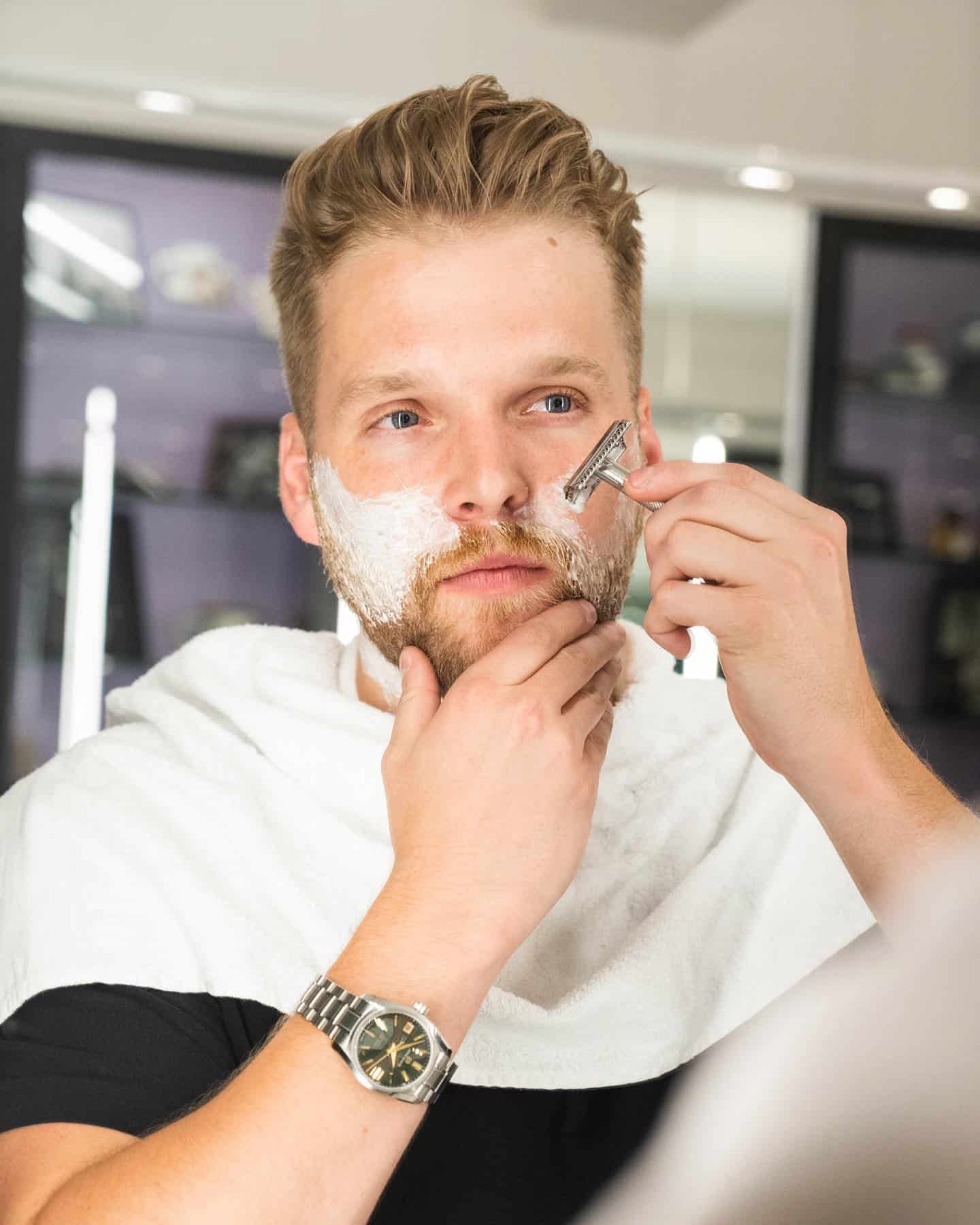 a man shaving his beard in front of the mirror