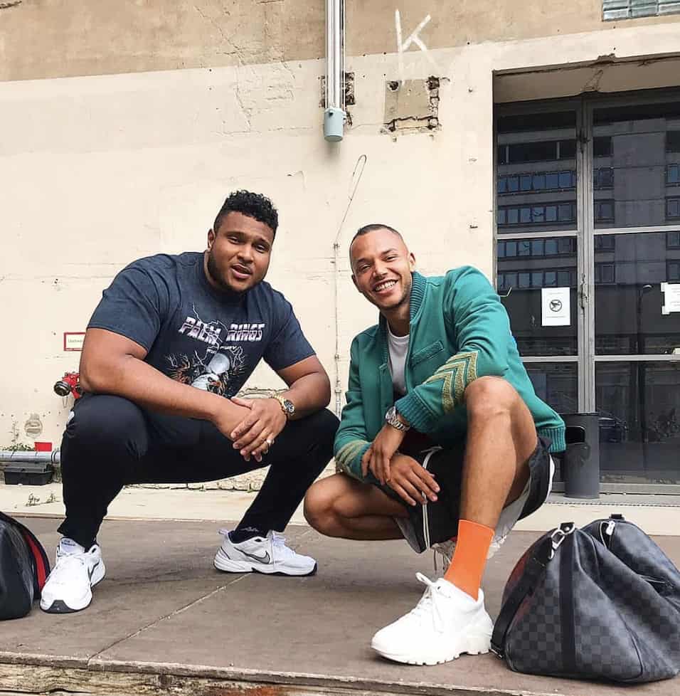 two men squating down, smiling