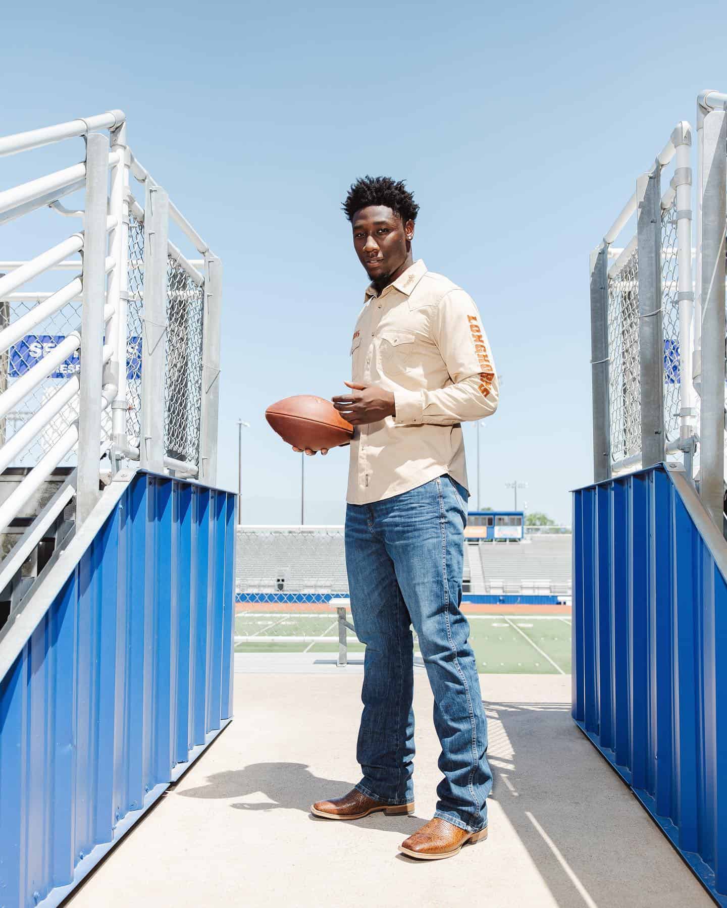 a tall man holding a rugby ball