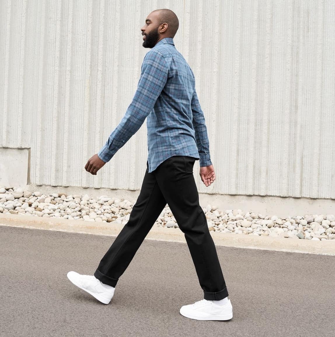 man walking away from the camera in a flannel and jeans.