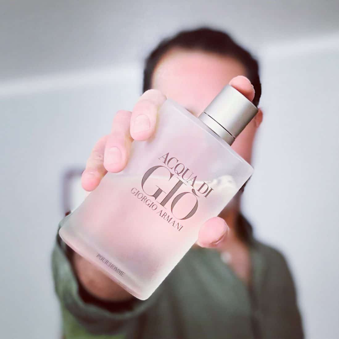 man holding out a bottle of acqua di gio pour homme