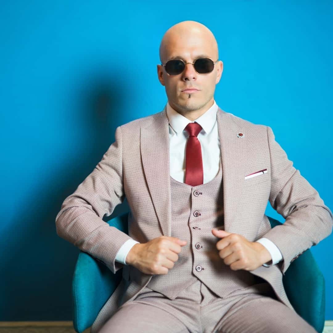 a man in suit and glasses with a cleans shaved head