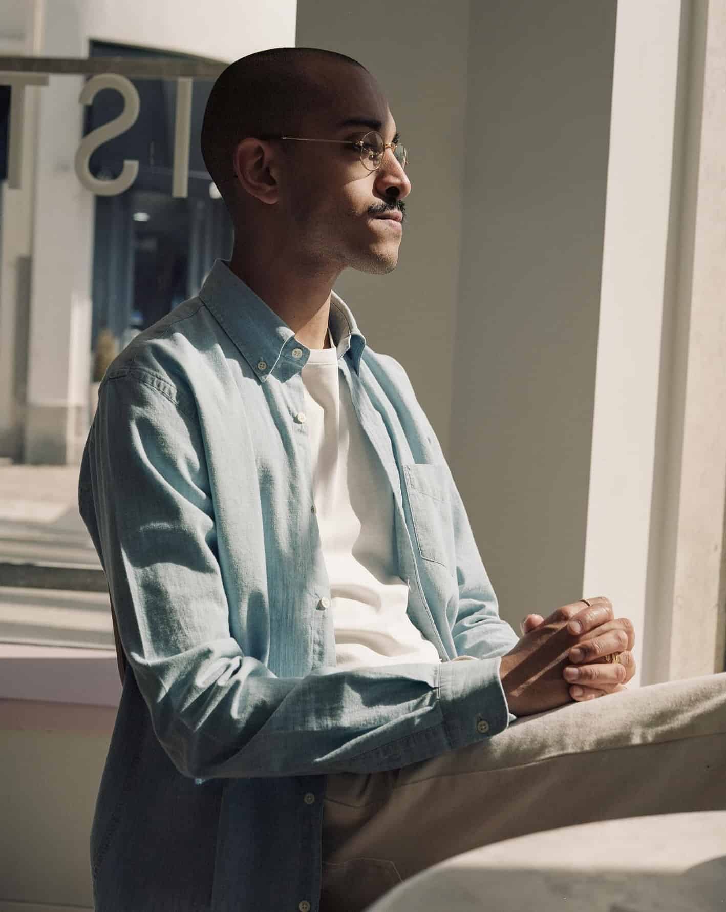 man wearing a light blue shirt over a white t-shirt