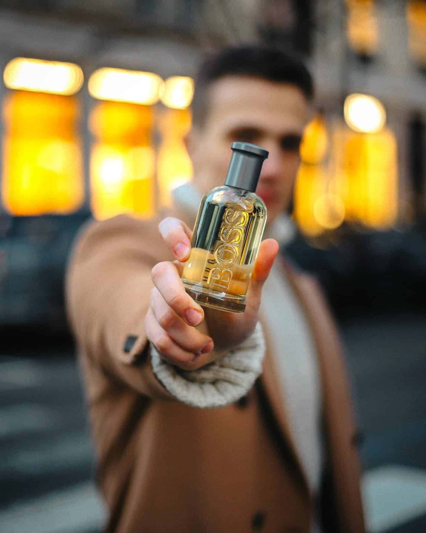 holding out a hugo boss bottled cologne