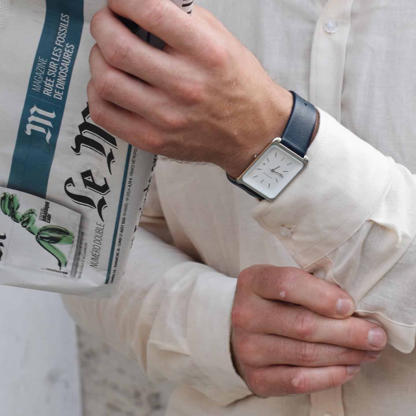 man wearing a linen shirt holding a newspapers