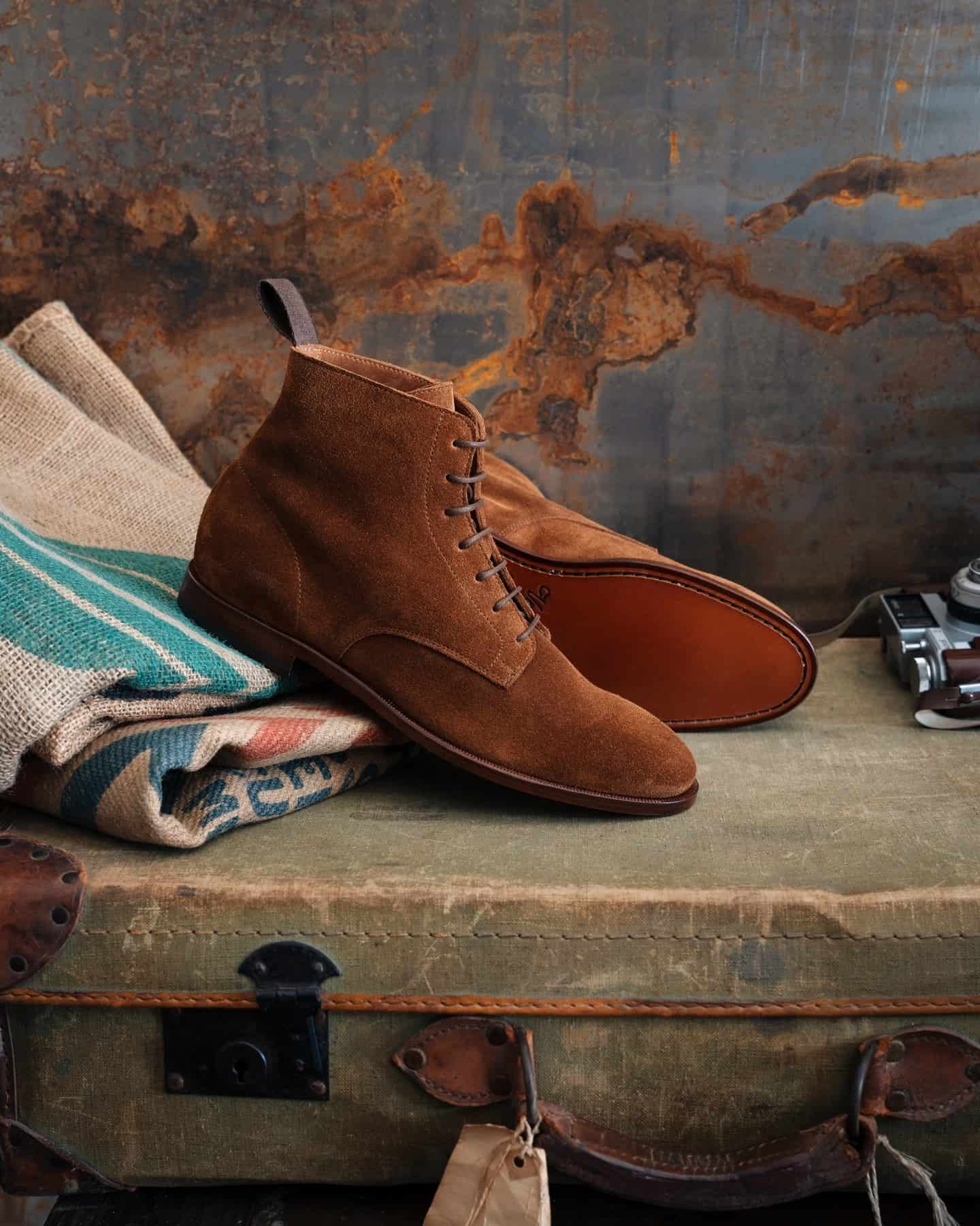 brown suede boots on top of a luggage