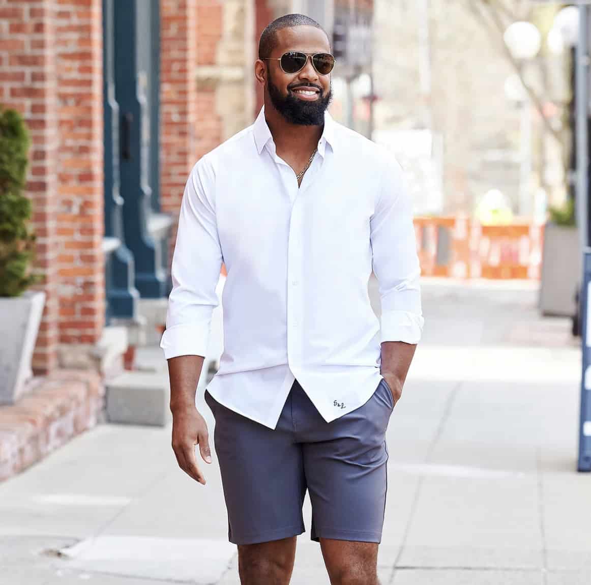 man walking down street in sunglasses smiling 
