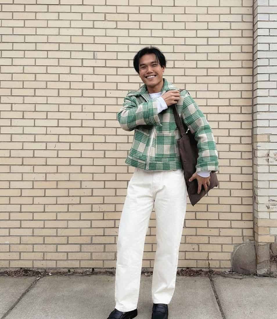 man smiling, holding a shoulder bag 