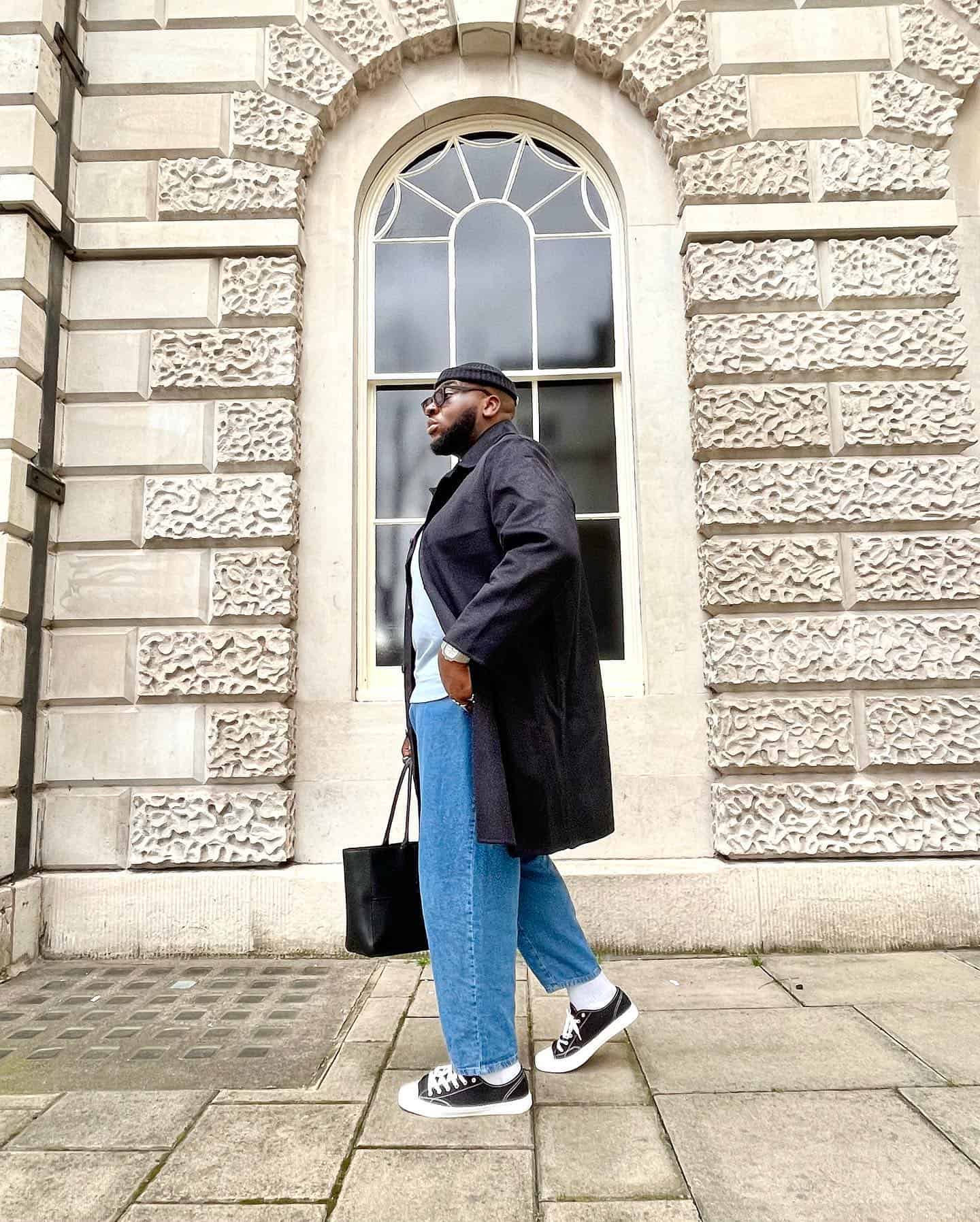 man in an overcoat carrying a tote bag