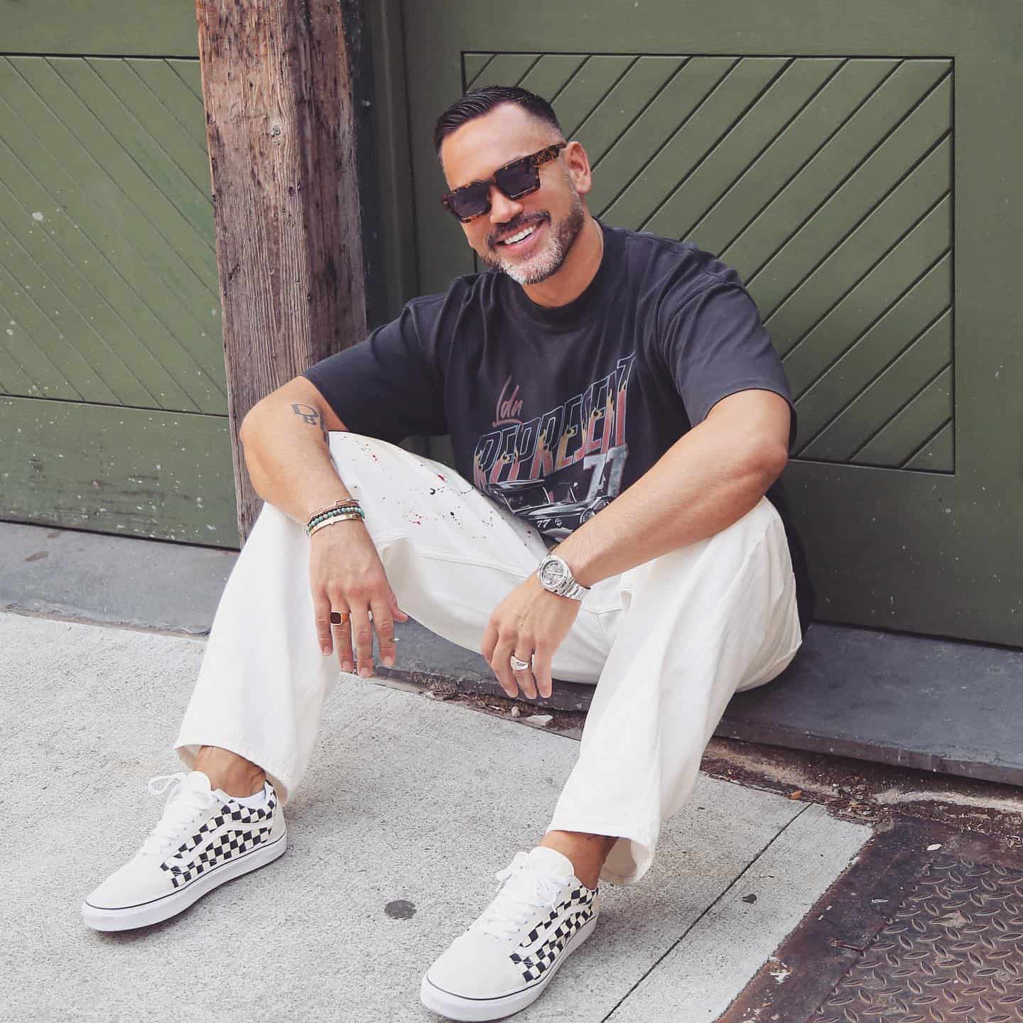 man in glasses sitting on the sidewalk