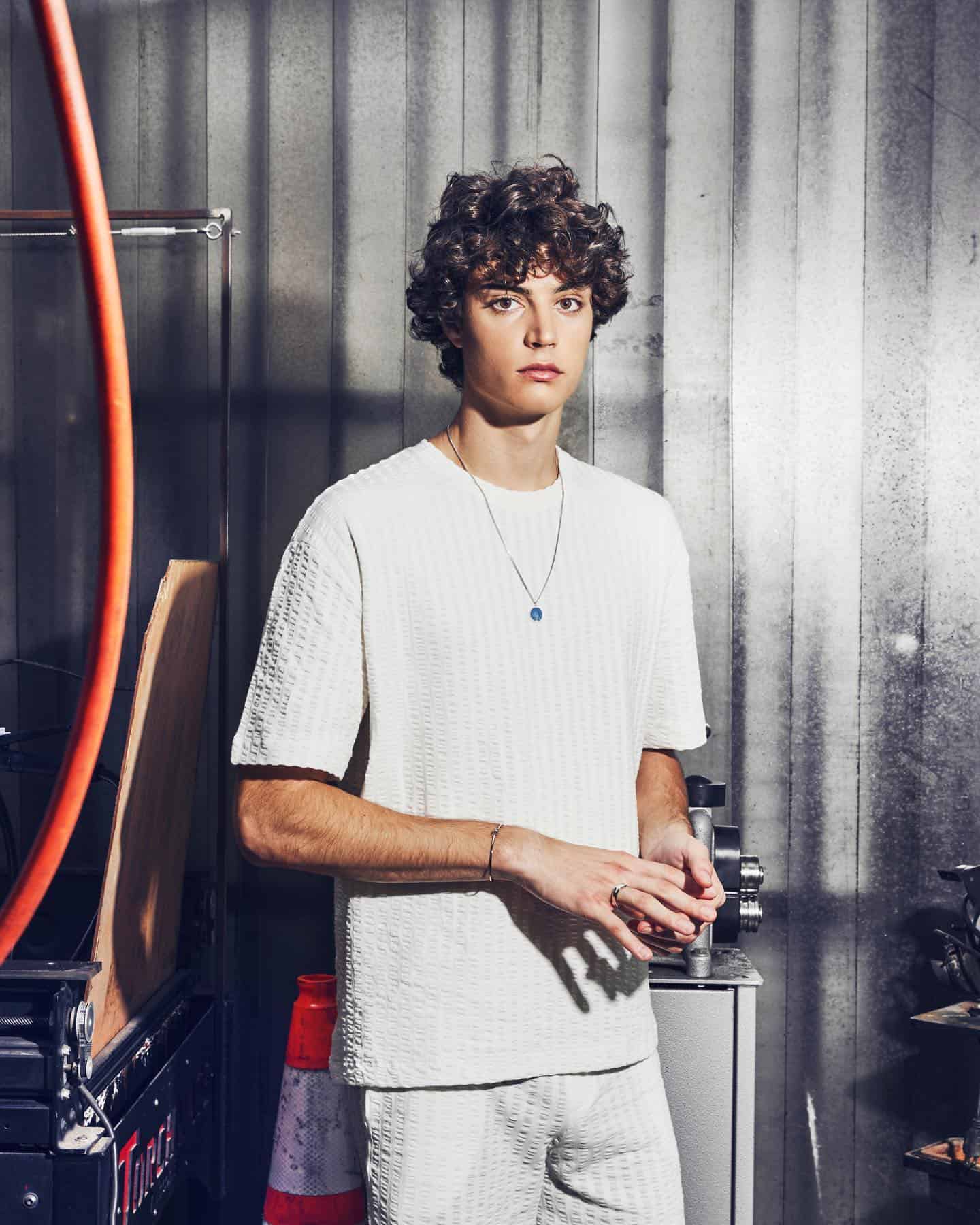 man with curly hair in white outfit
