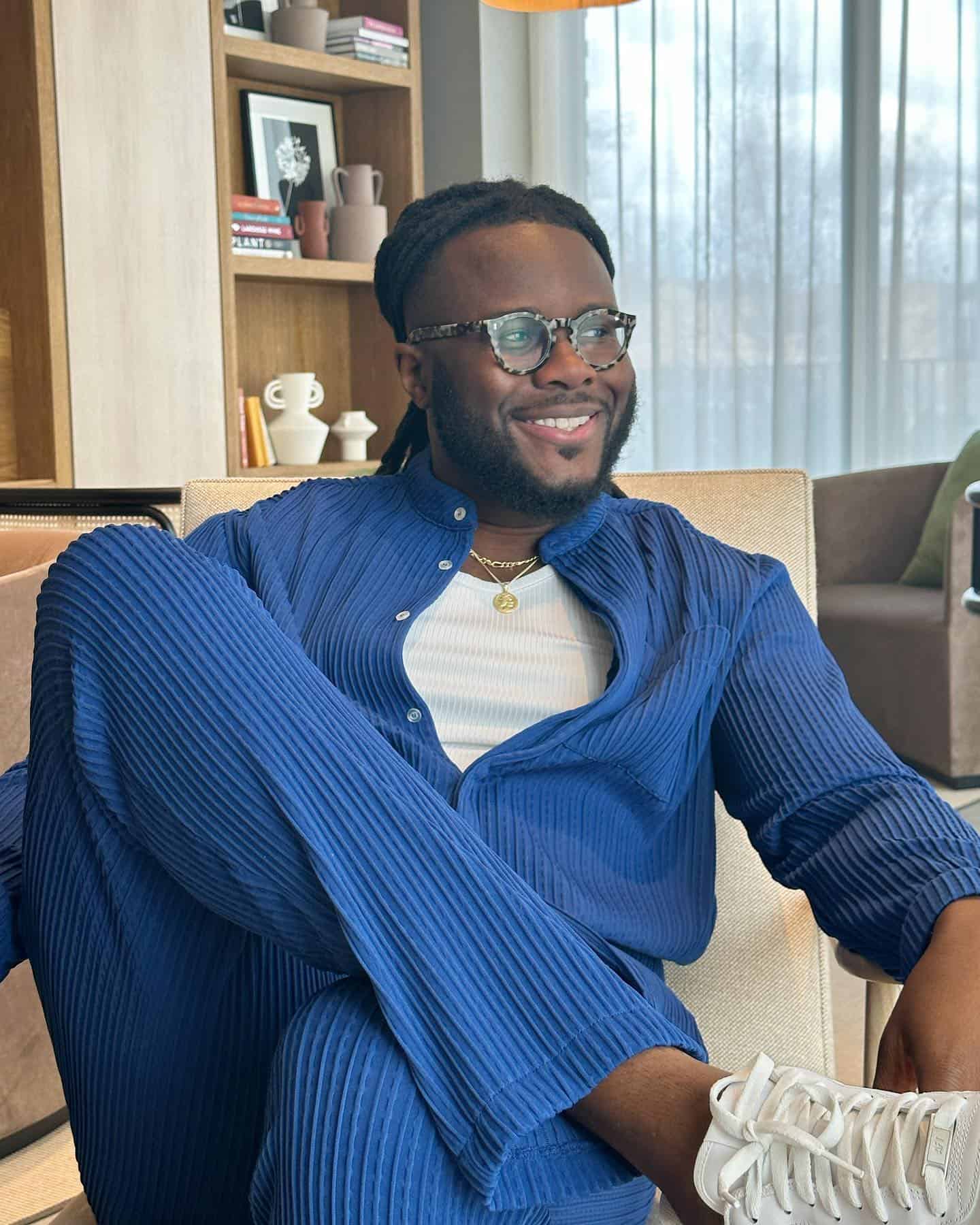 man in blue sitting with legs crossed