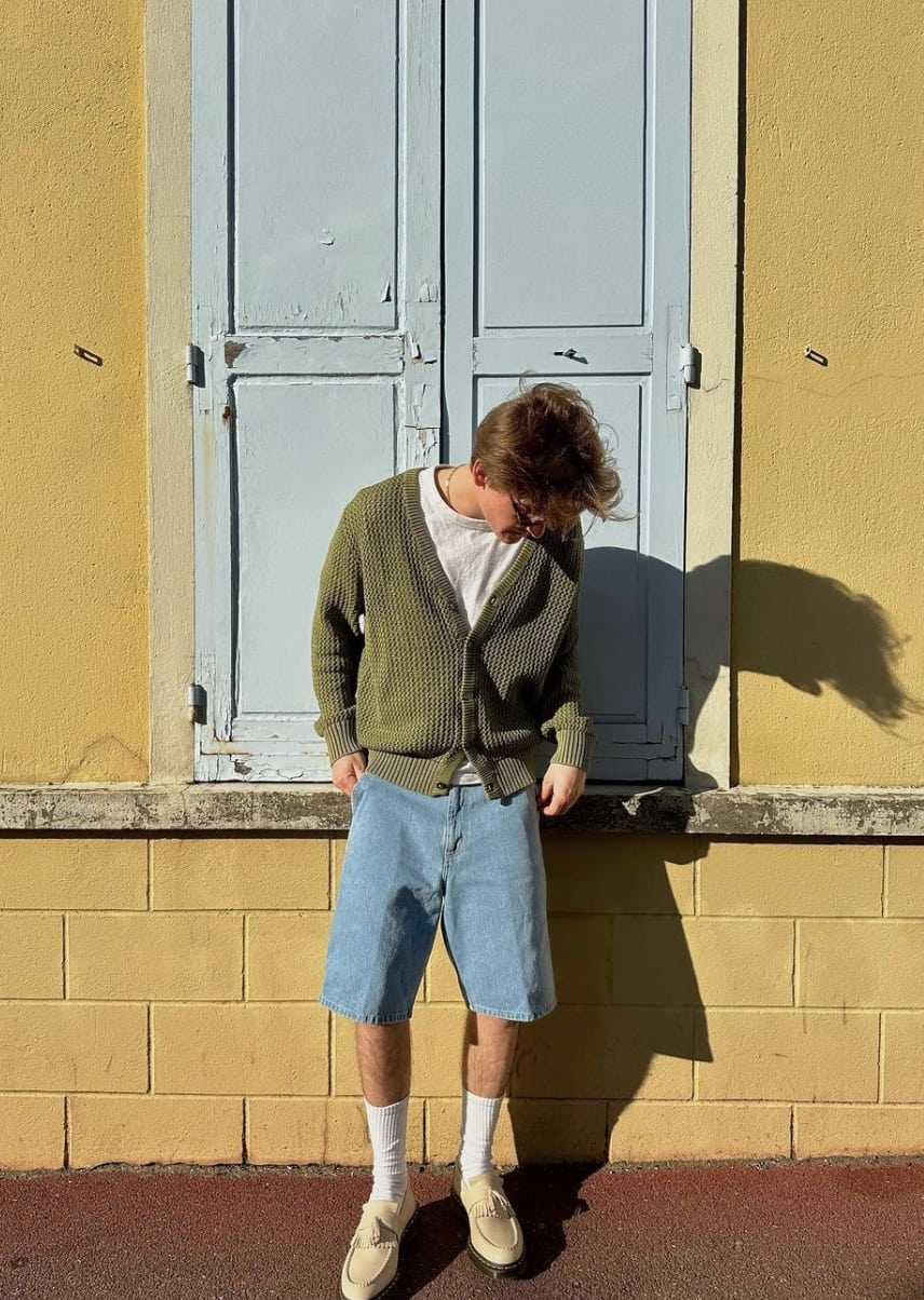 man leaning against a yellow wall looking down
