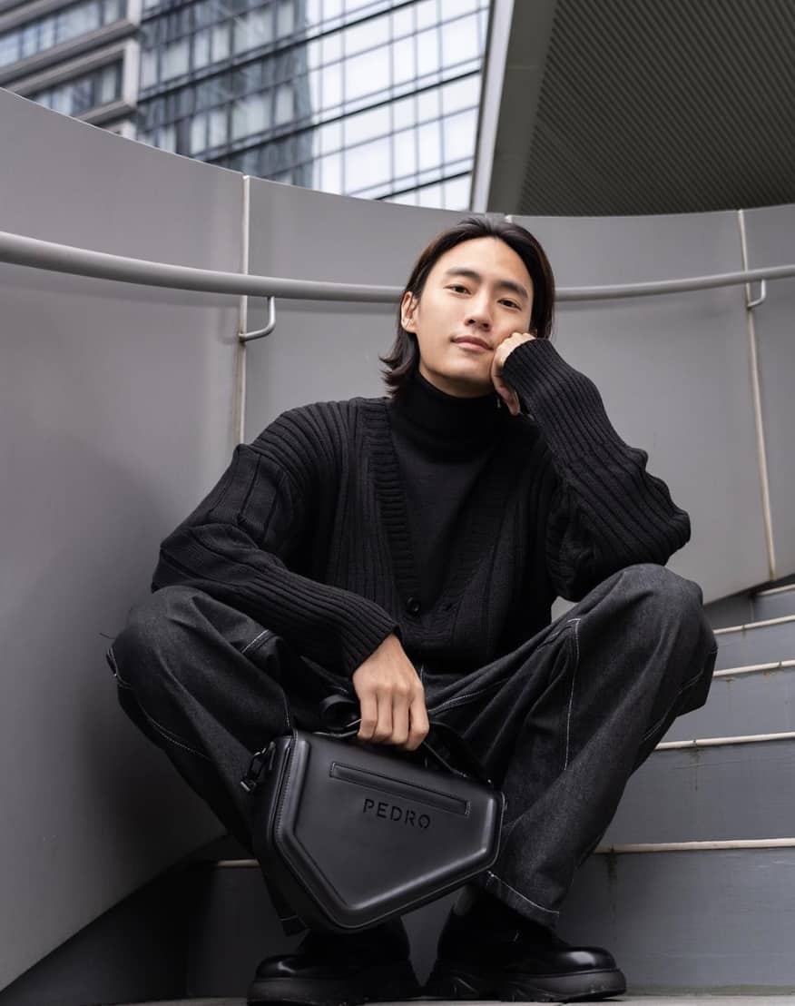 man sitting on stairs, wearing all black and pedro shoes