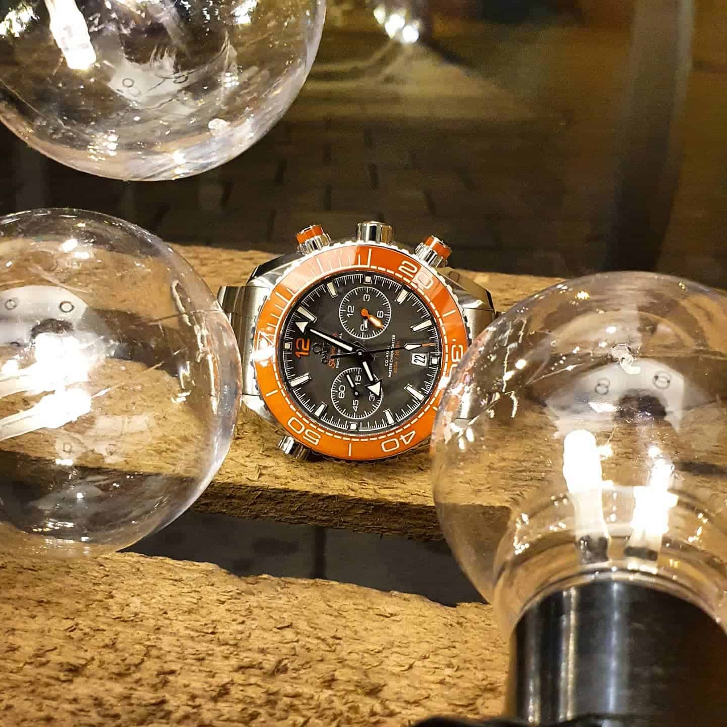 an Omega Seamaster Planet Ocean Chrono watch behind light bulbs