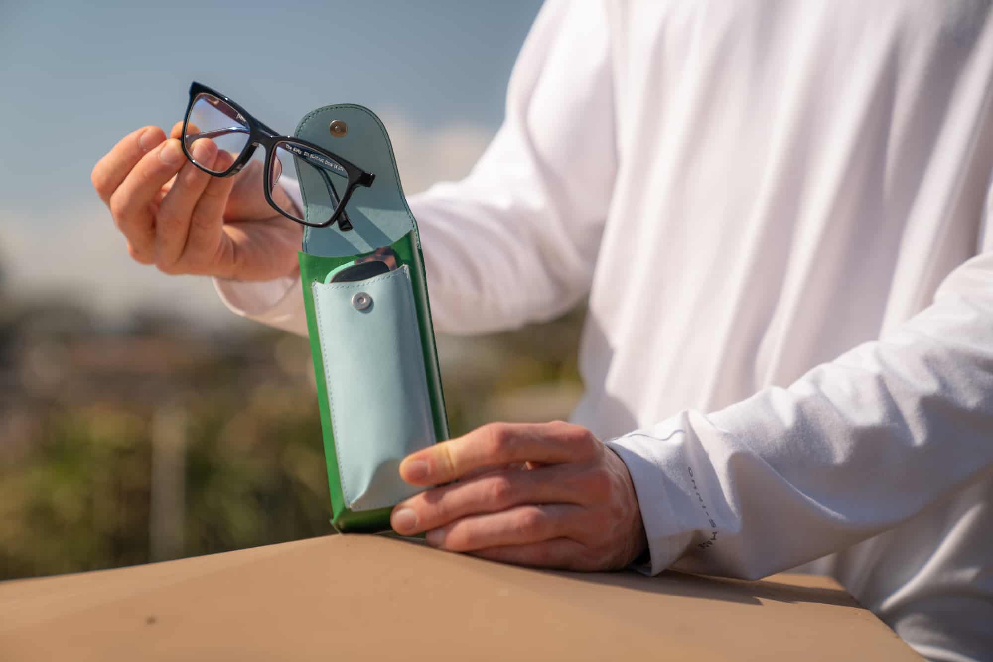 sunglasses being pulled out of a case, outside 