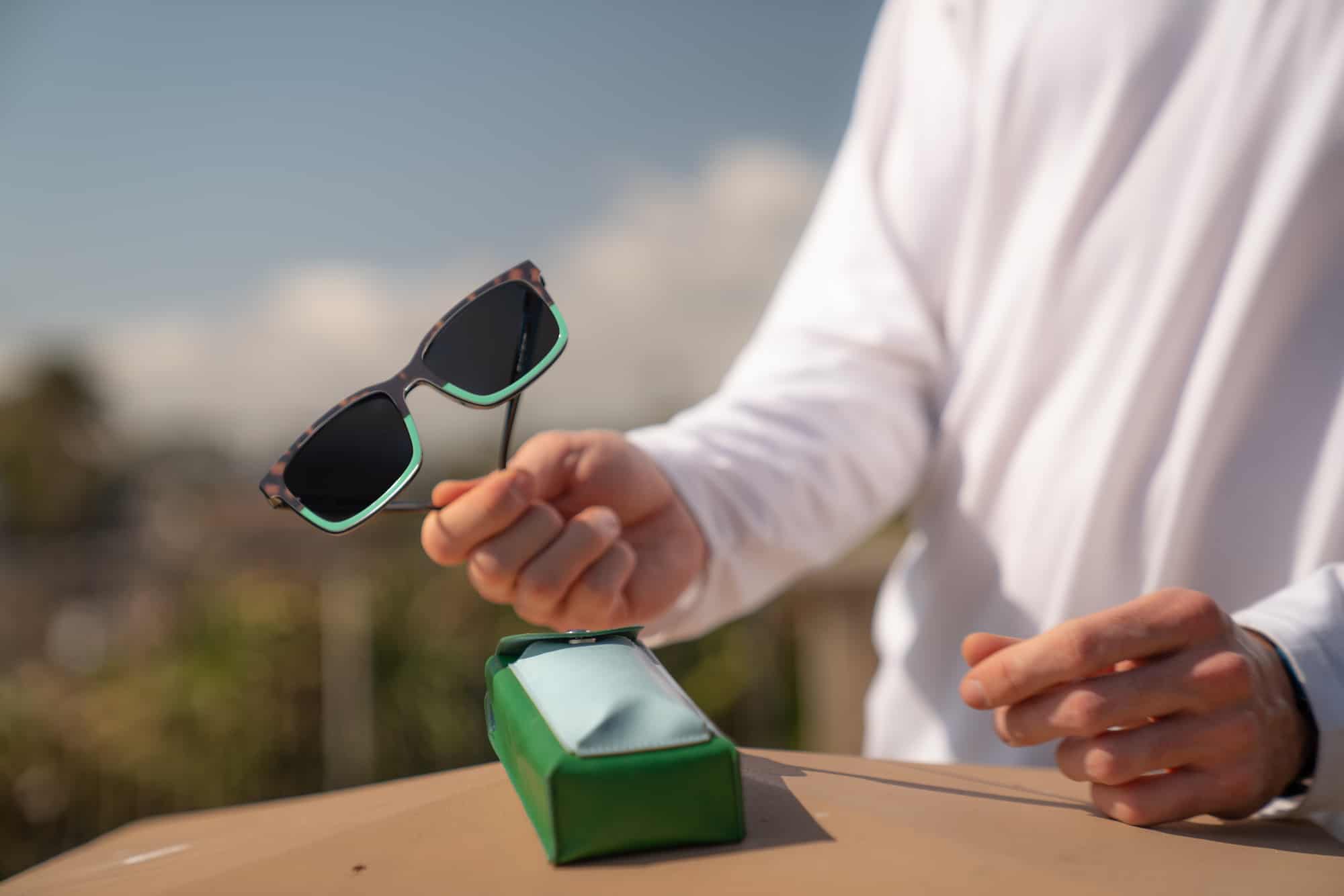man holding sunglasses outside 