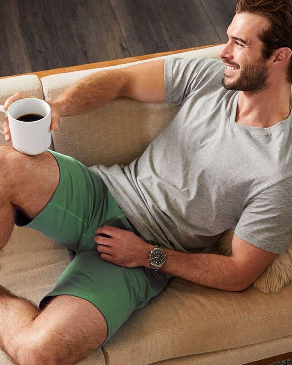 man sitting on a couch while holding a cup of coffee