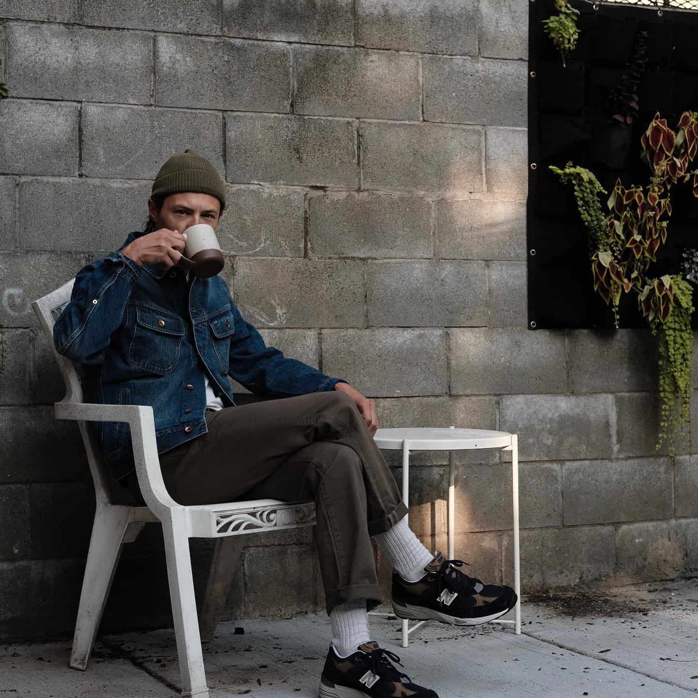 man in denim jacket drinking from a cup