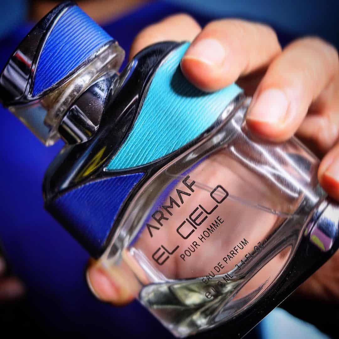 holding a bottle of armaf el cielo pour homme