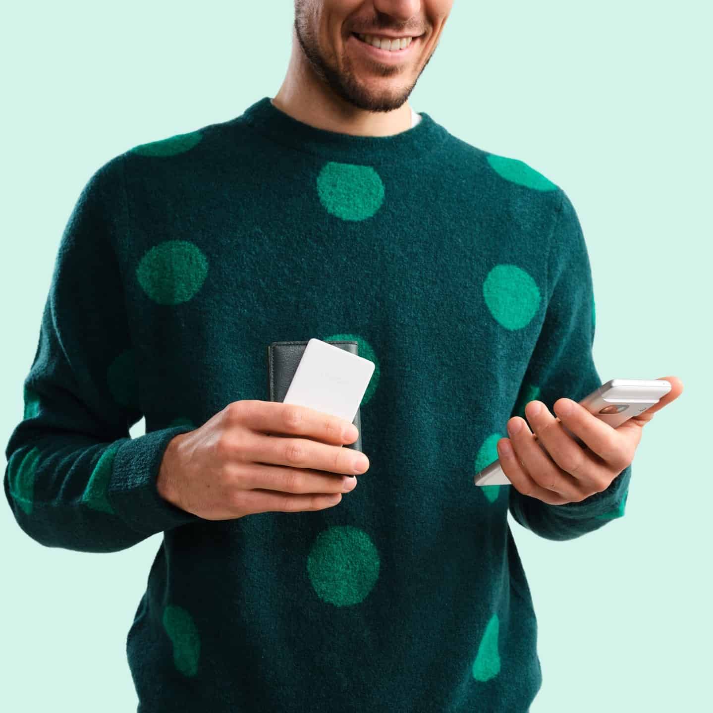 man holding his phone and wallet tracker