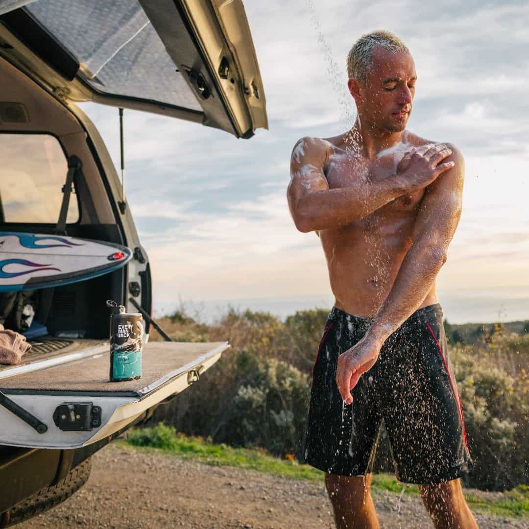 man taking a shower behind a truck