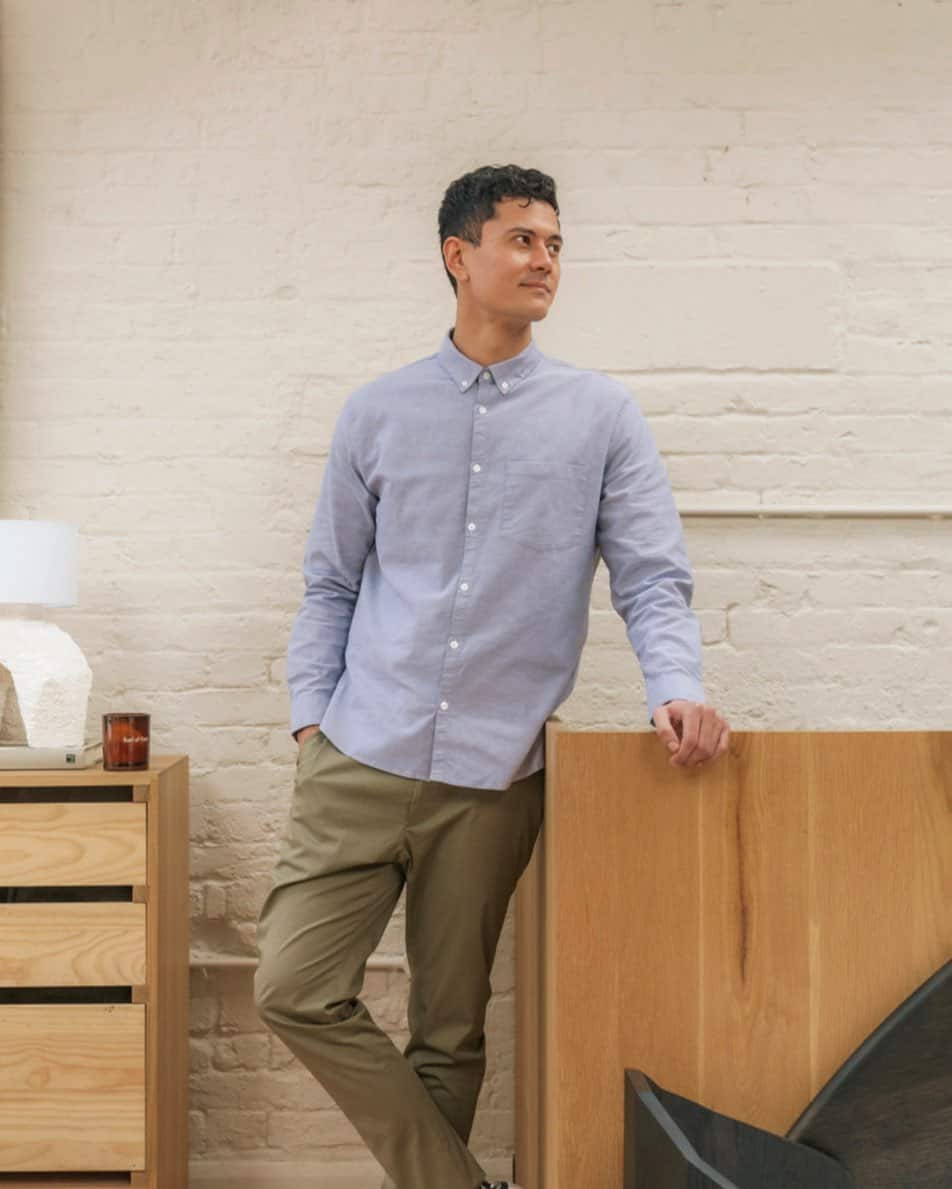 man in a blue shirt standing crossed leg