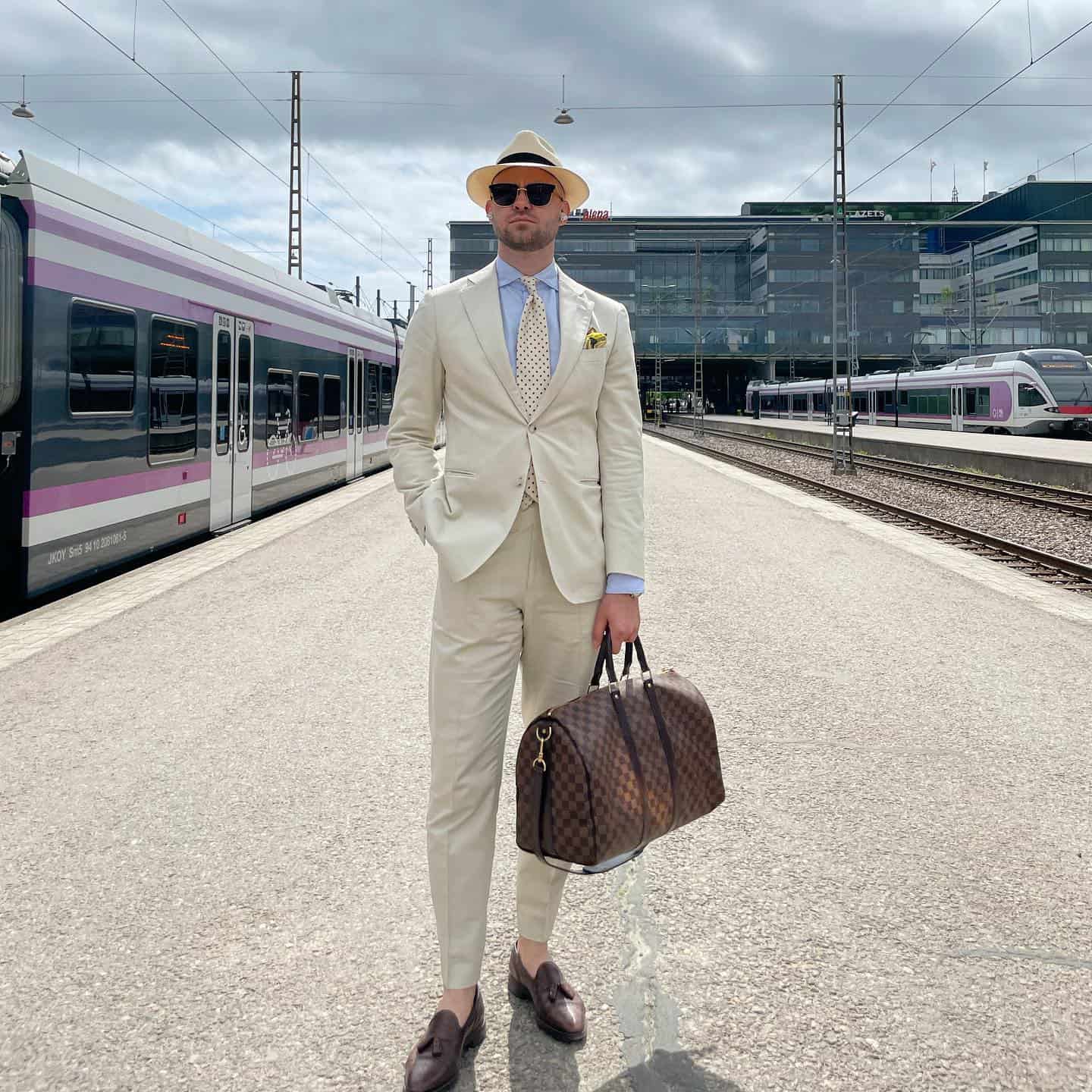man in a white suit carrying a weekend bag