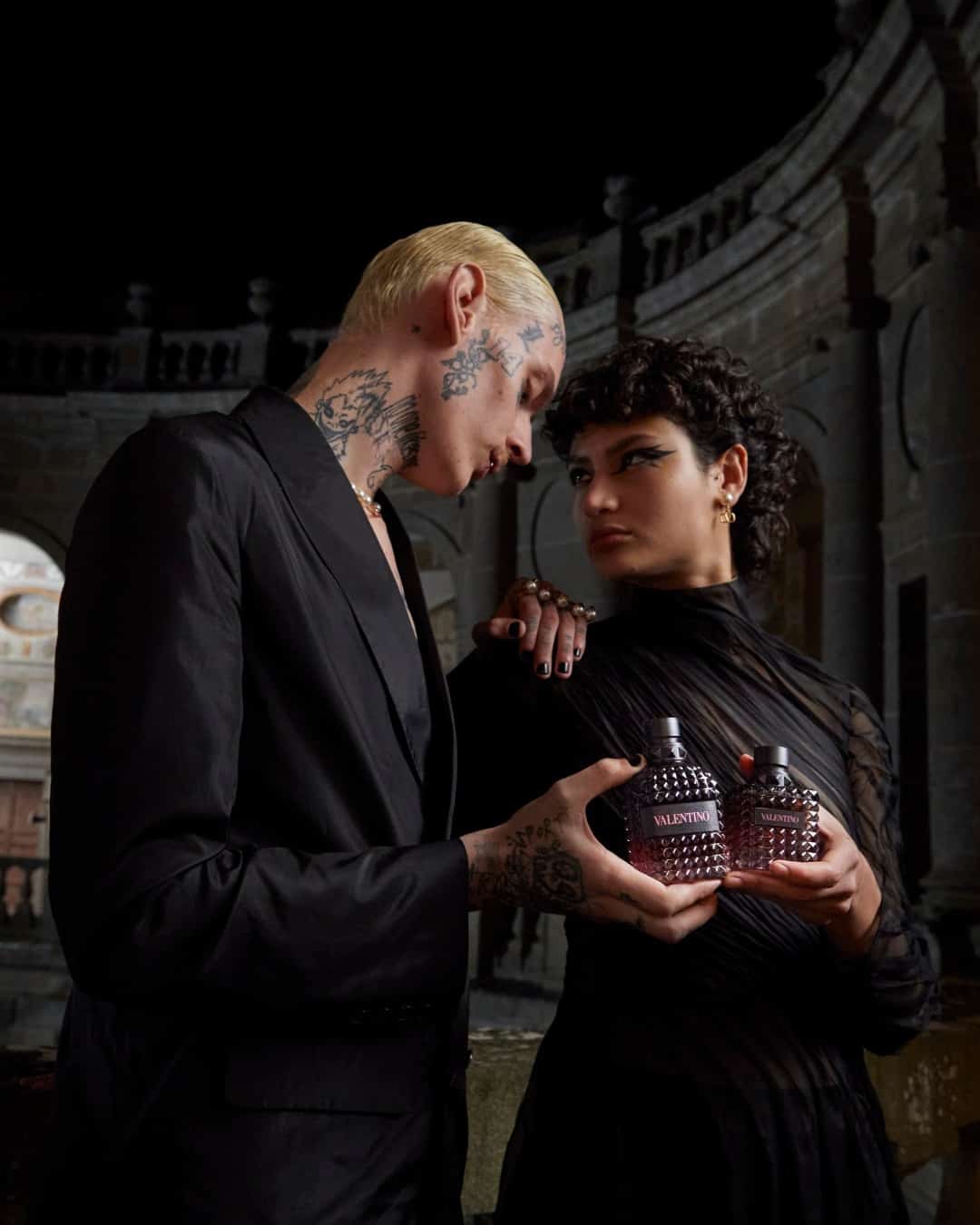 couple holding bottles of valentino oumo fragrance