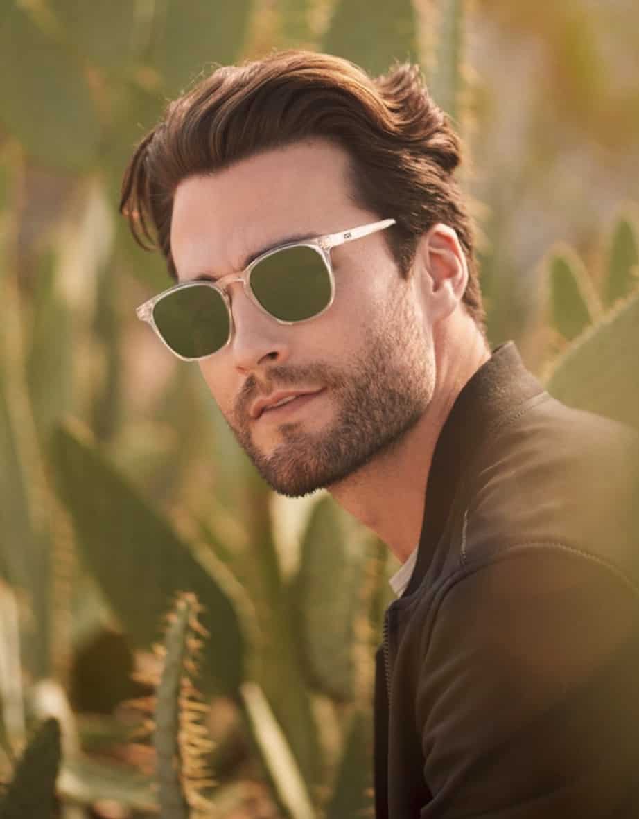 man looking at the camera wearing sunglasses outside near cactus