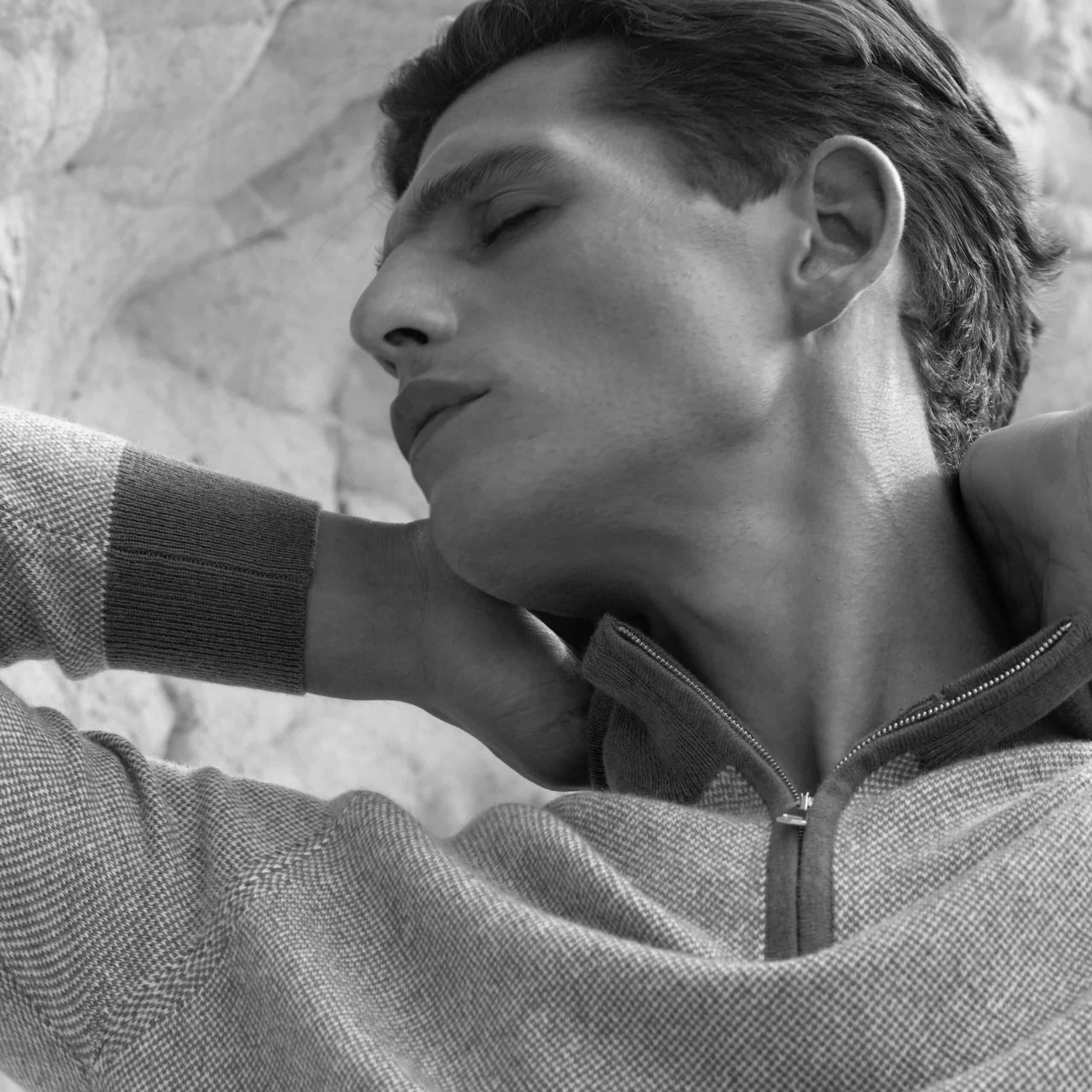 man with eyes closed massaging his neck