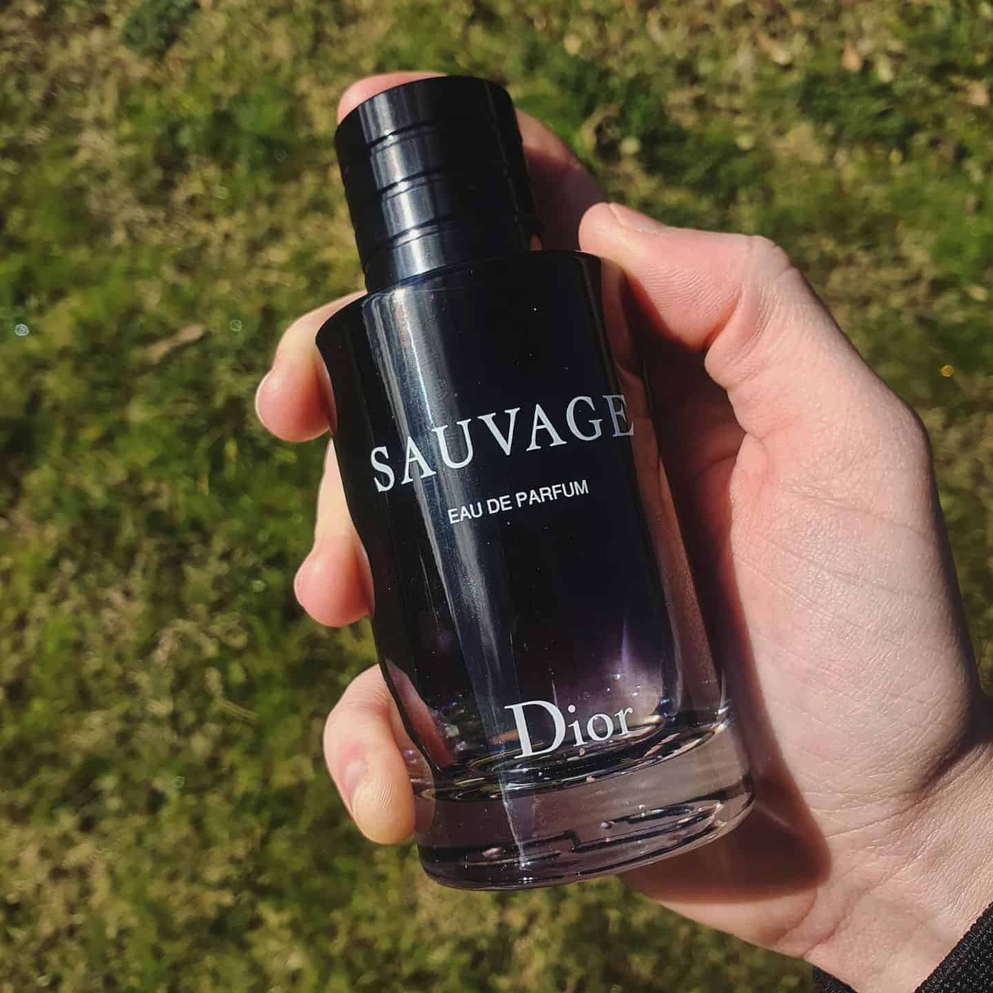 holding a bottle of sauvage eau de parfum by dior