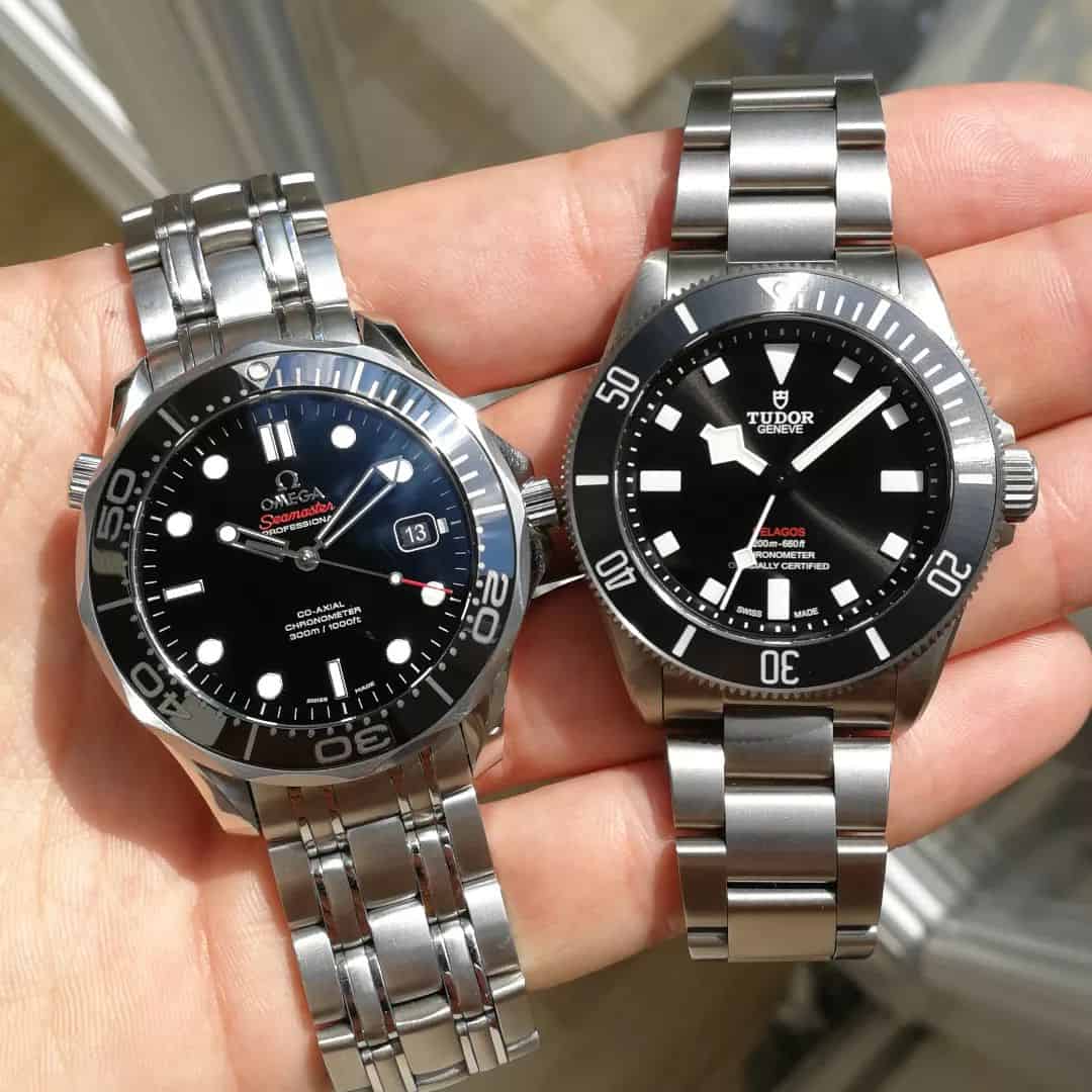 holding an omega and tudor titanium watches