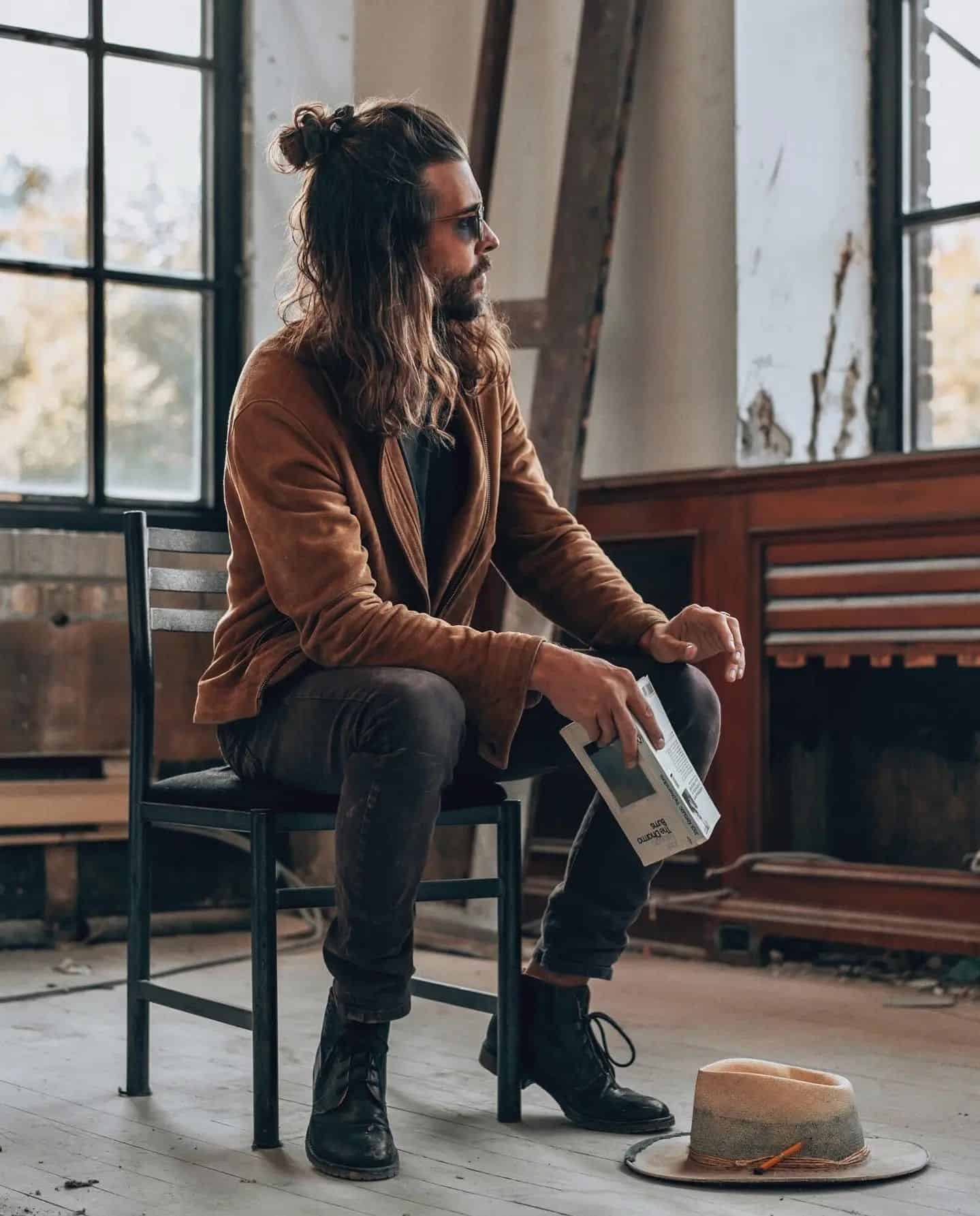 man with long hair sitting on a chair