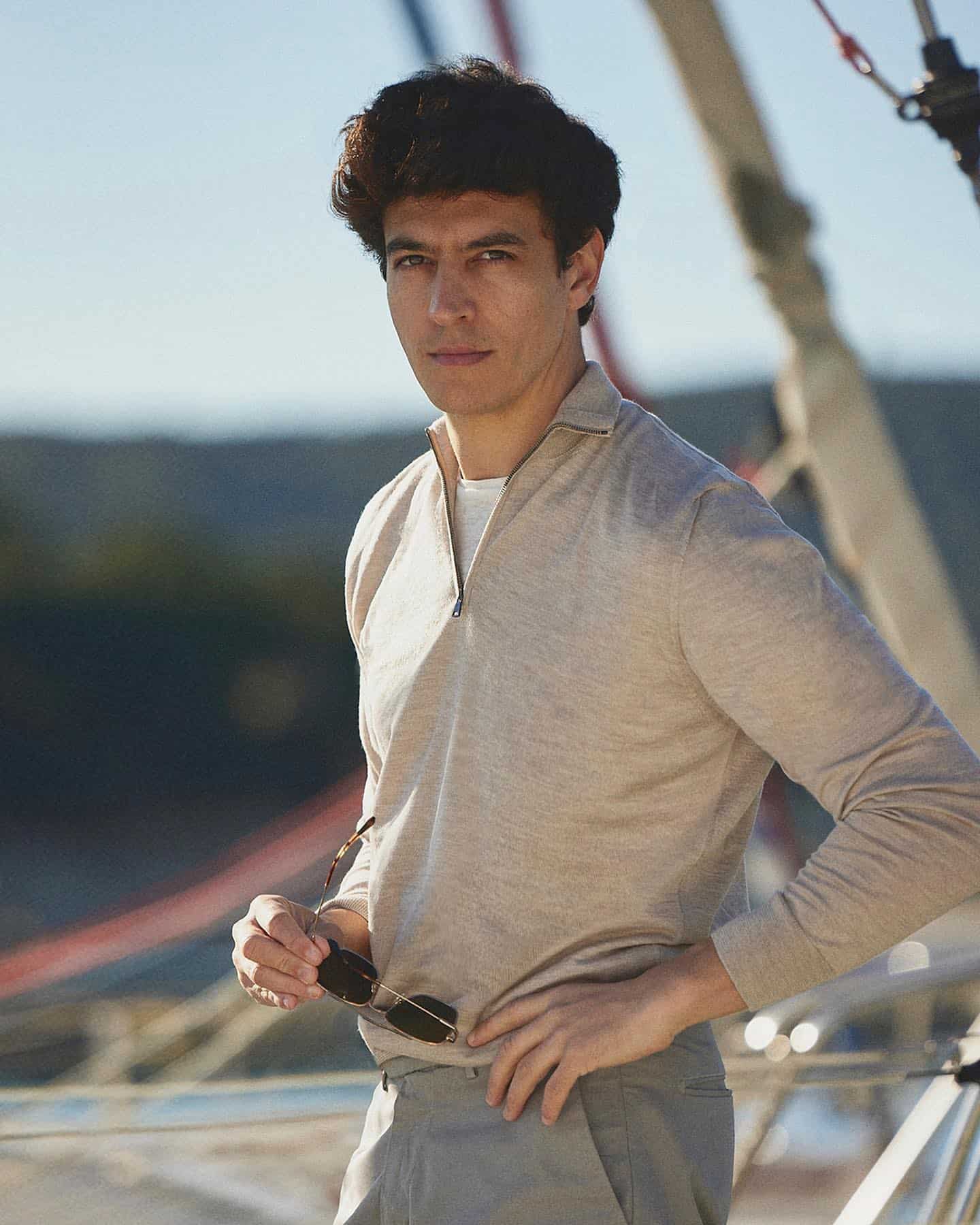 man wearing a zip up jumper holding a sunglass