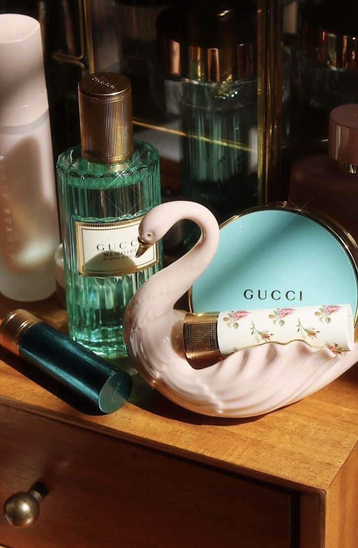 Bottle if Gucci Mémoire d'une Odeur on a shelf next to a decorative swan and other beauty items