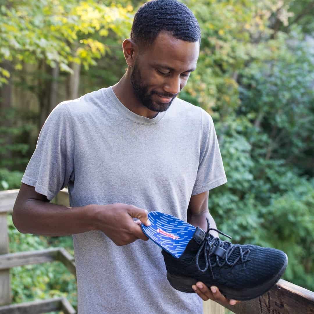 man inserting an insole to his sneakers