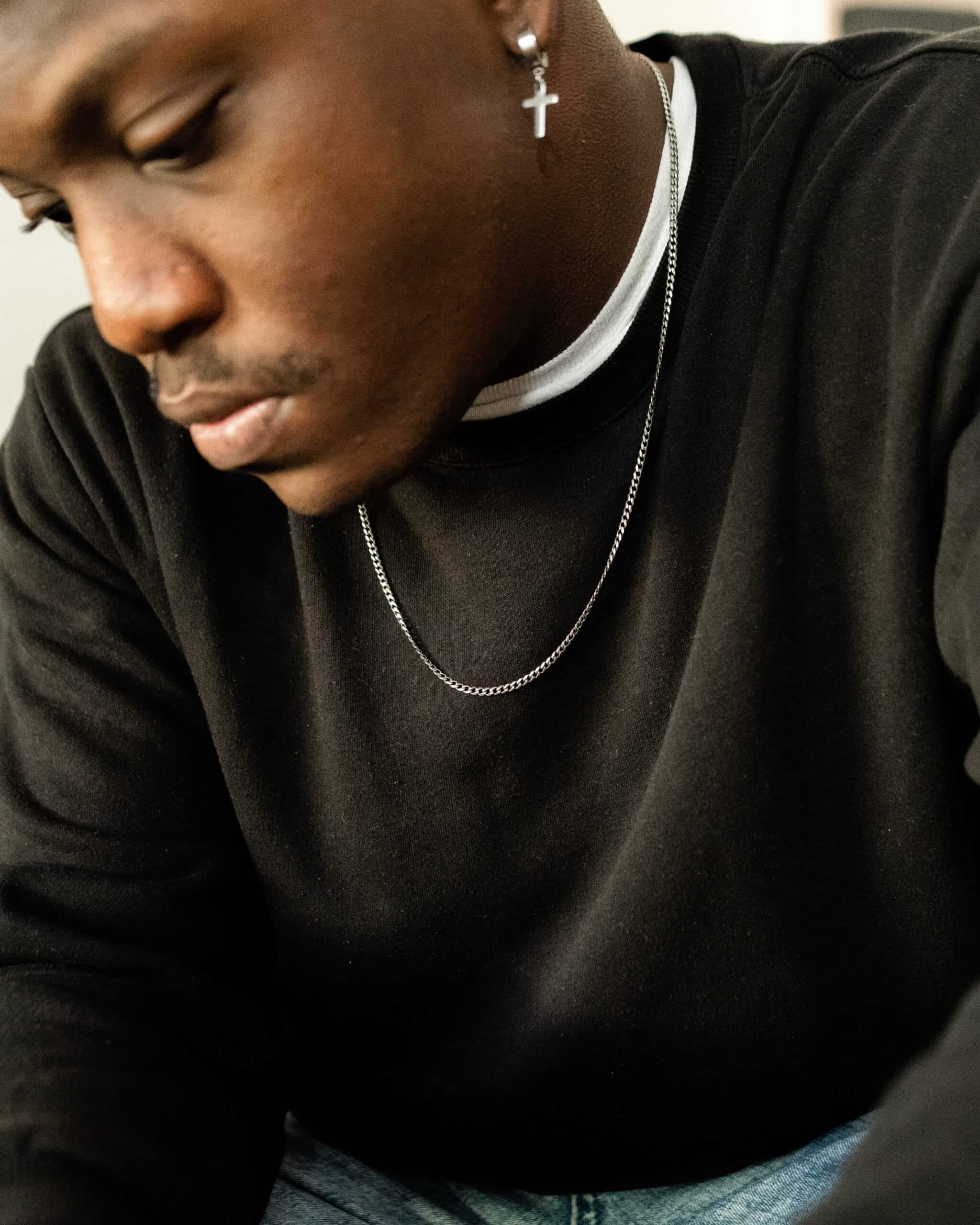 man looking down wearing a curb chain