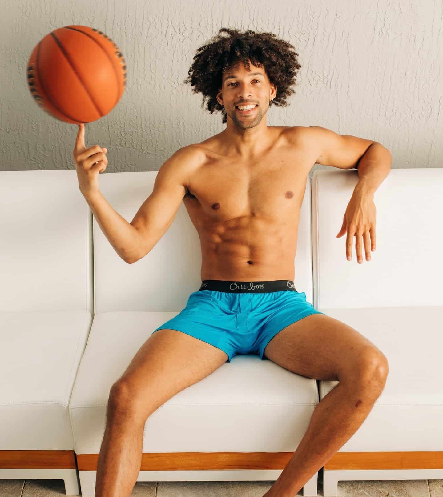 man on the sofa spinning a basketball with his finger