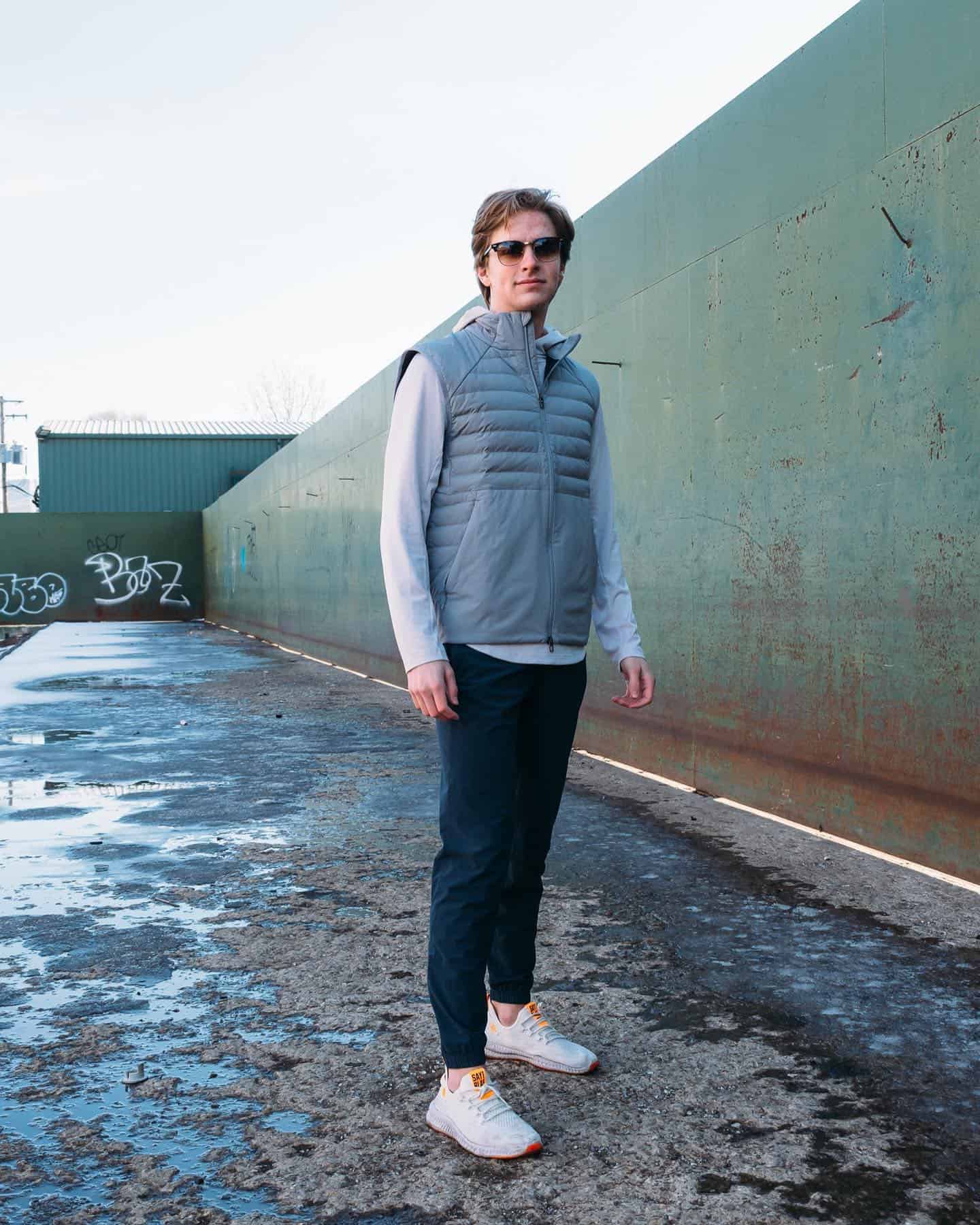 man wearing grey quilted vest and navy joggers