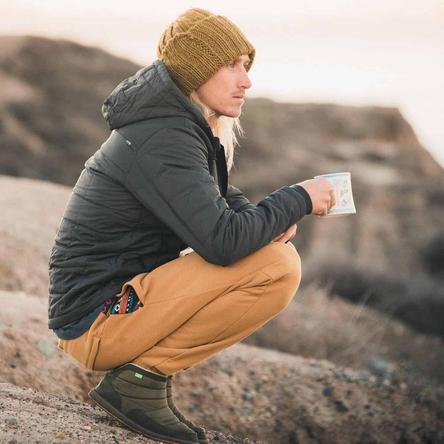 man holding a cup on top of a mountain