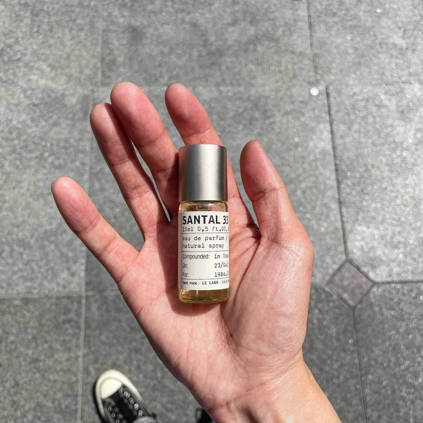 holding a small bottle of santal 33 by le labo