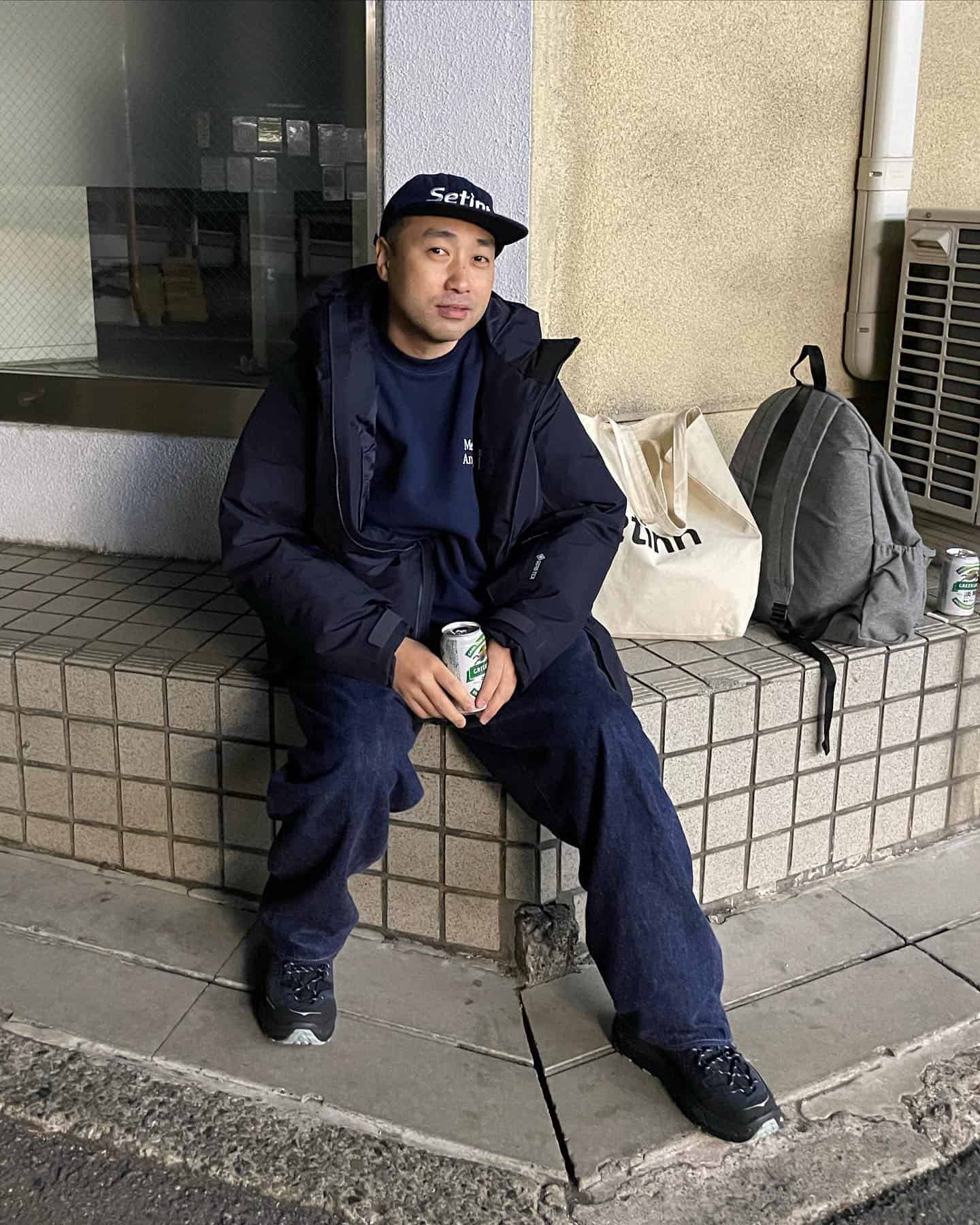 man in a navy puffer jacket sitting on a concrete bench