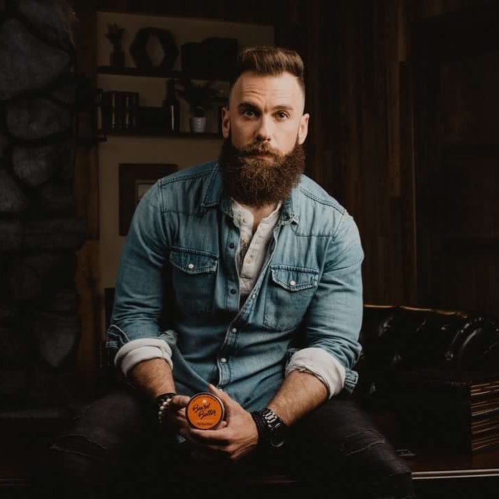 man holding a can of beard butter