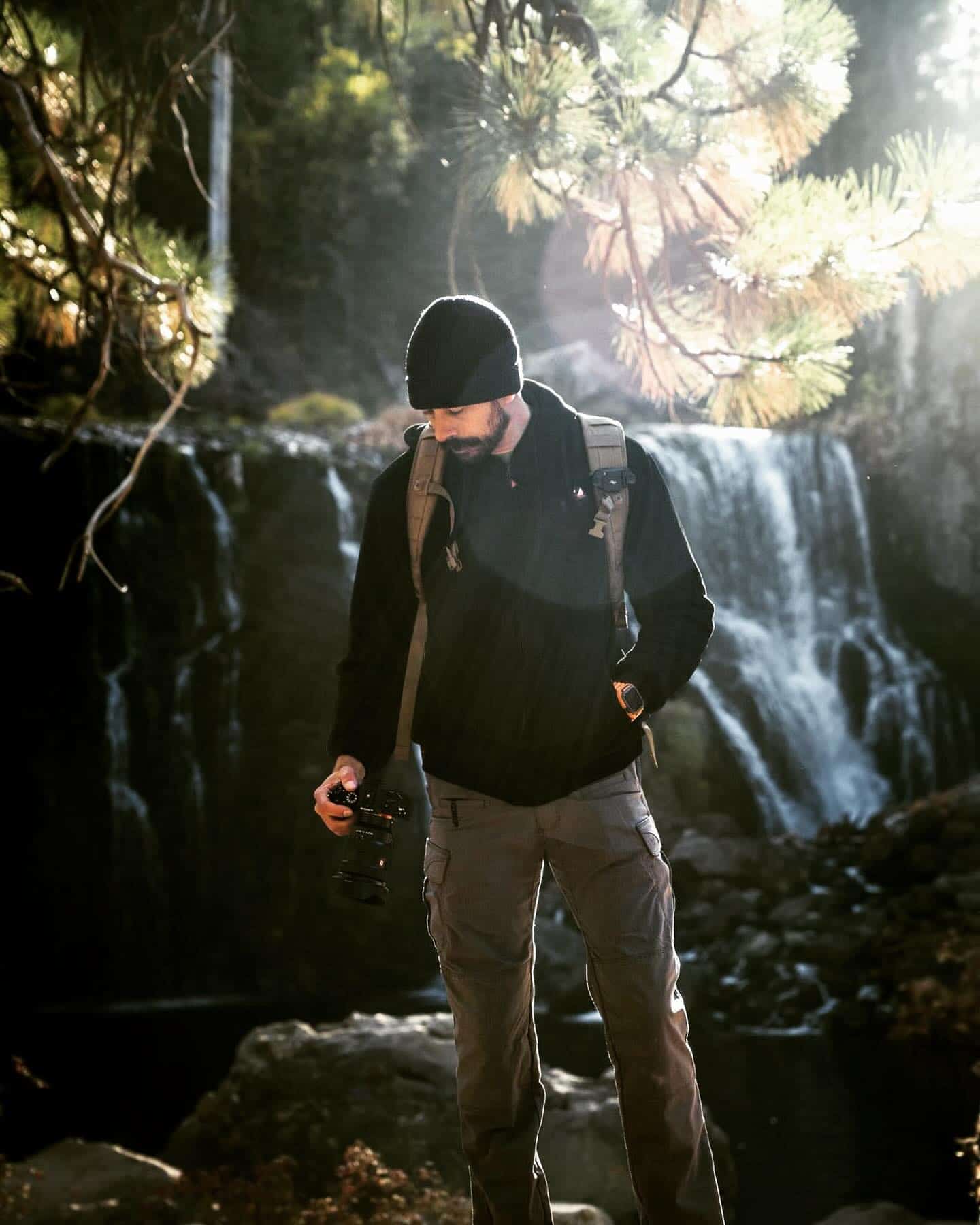 photographer holding a camera in front of a waterfalls