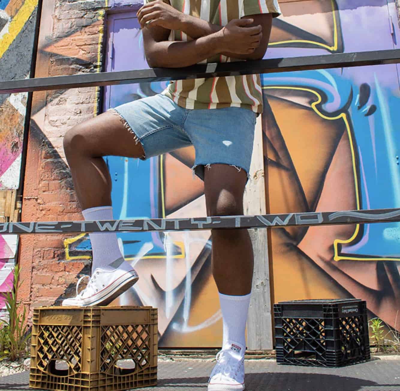 man leaning on a railing wearing cut off shorts from Mugsy