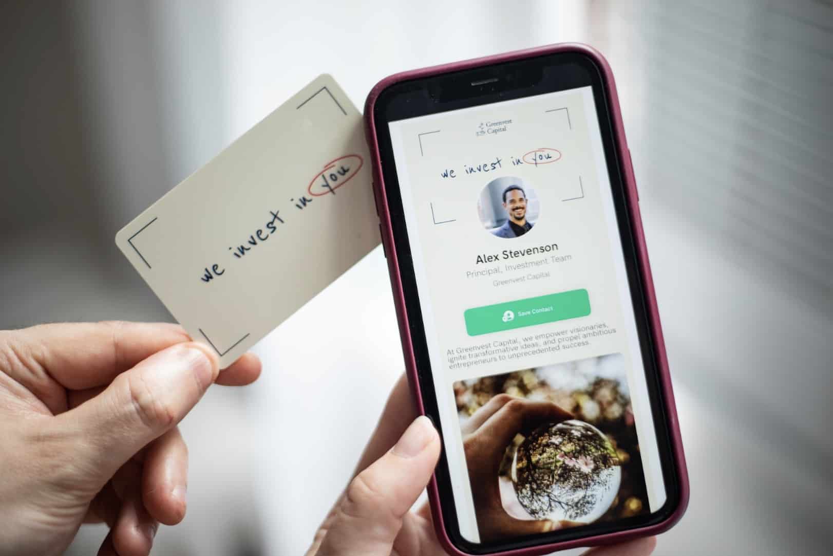 Two people sharing a digital business card, showing information on a phone