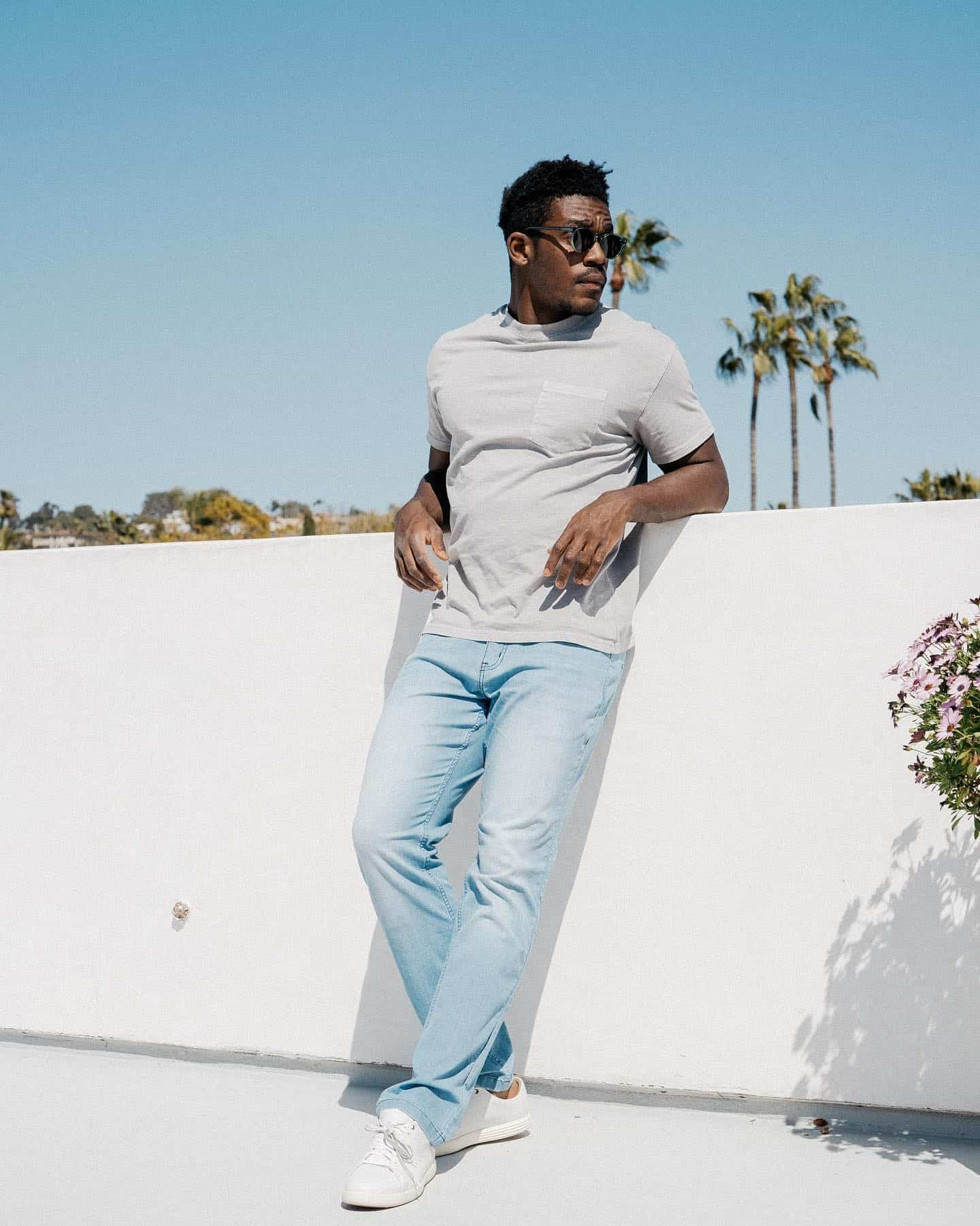 man leaning against a wall wearing Mugsy jeans