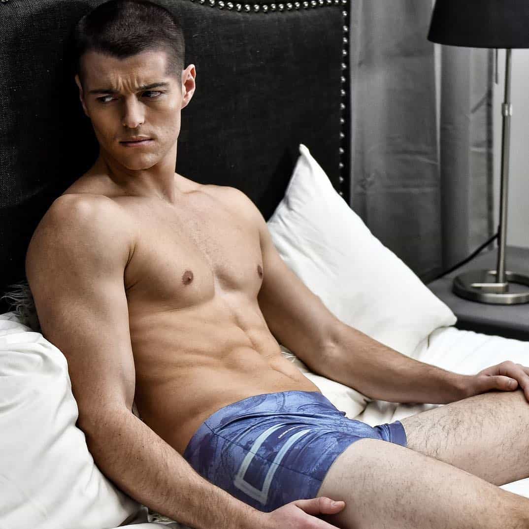 man in underwear sitting on a bed