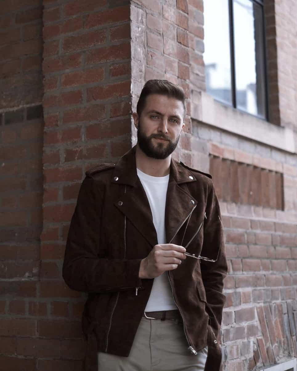 Man wearing leather jacket and slacks, looking at the camera 